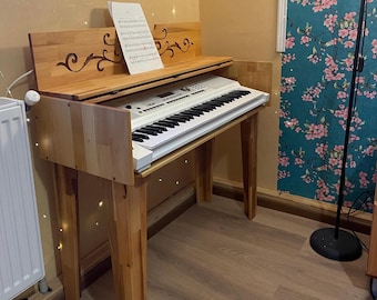 Könnte beinhalten: Eine weiße elektronische Tastatur mit einem Holzständer. Der Ständer hat ein dekoratives geschnitztes Design auf der Oberseite und ist aus hellem braunem Holz gefertigt. Die Tastatur steht auf einem hellbraunen Holzboden.