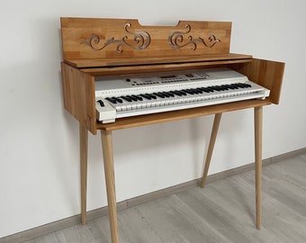 Könnte beinhalten: Ein weißes elektronisches Keyboard mit einem Holzständer und einer dekorativen Holzplatte mit einem geschnitzten Design. Das Keyboard steht auf einem hellen Holzboden.