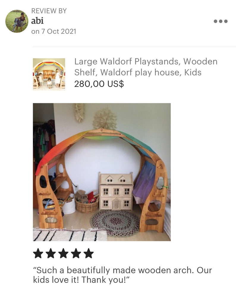 May include: A wooden playhouse arch with a rainbow fabric canopy. The arch has shelves and a small wooden dollhouse inside. The playhouse is on a rug with a white and gray striped rug underneath. "Such a beautifully made wooden arch. Our kids love it! Thank you!"