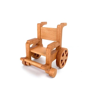 Könnte beinhalten: Ein hölzerner Spielzeug-Rollstuhl mit brauner Oberfläche. Der Rollstuhl hat ein einfaches Design mit Sitz, Rückenlehne und Rädern.