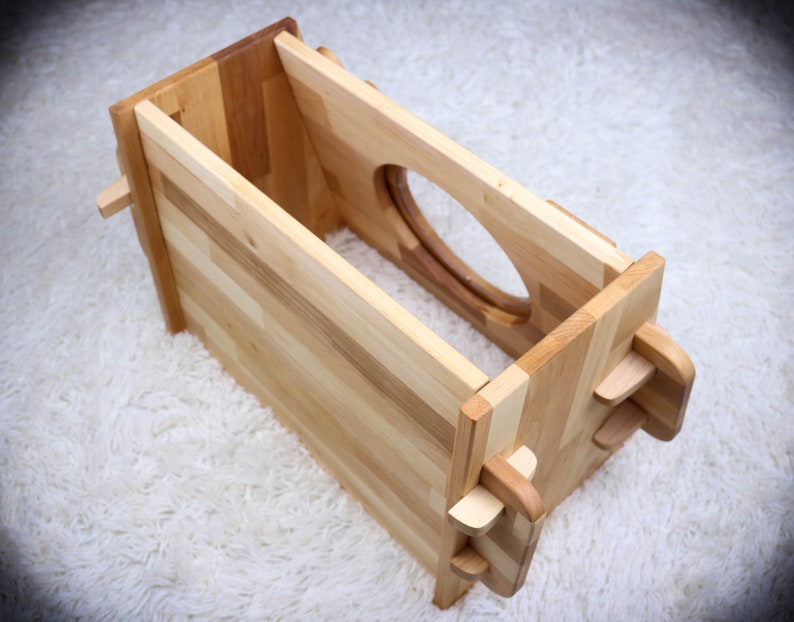 May include: A wooden box with a cutout in the front and a latch on the side. The box is made of light wood and has a natural finish.