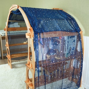 May include: A wooden play structure with shelves and a blue fabric canopy with white stars. The canopy is draped over the top of the structure, creating a cozy and inviting space for play.
