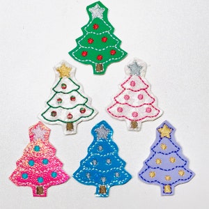 May include: Six embroidered Christmas tree iron-on patches in various colors and designs. The trees are green, white, pink, blue, and purple with gold and silver accents.
