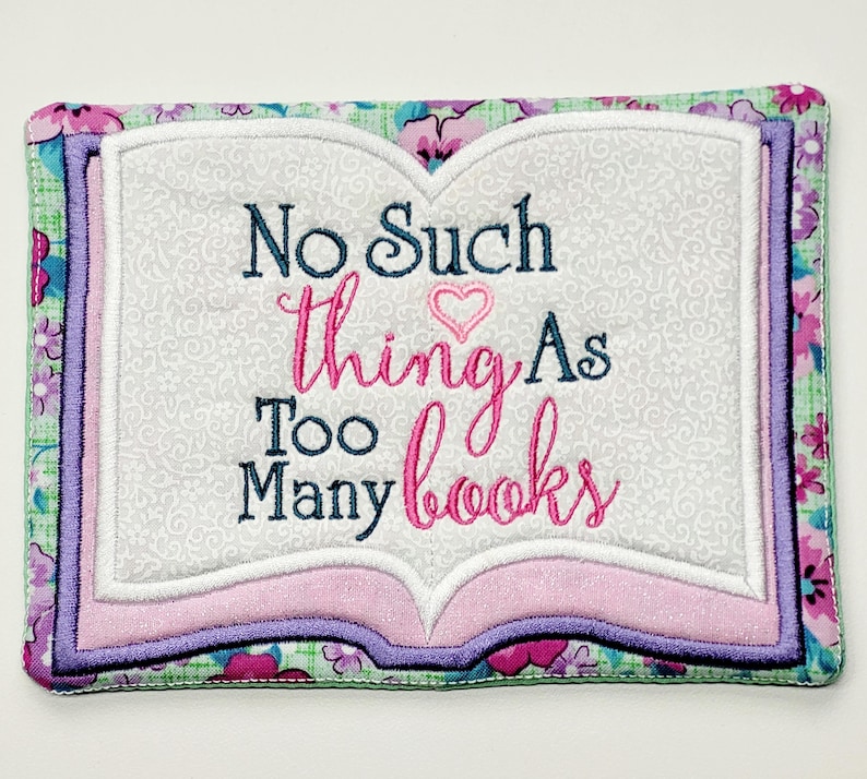 May include: A pink and green book-shaped coaster with the text "No Such thing As Too Many books" embroidered on it.