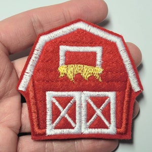May include: Red felt barn applique with white trim and a yellow cow inside. The barn has a white door with an X pattern.
