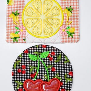 May include: Two embroidered fabric coasters. One coaster is pink and white gingham with a yellow lemon slice. The other coaster is black and white gingham with two red cherries.