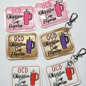May include: Six embroidered patches with the text "OCD Obsessive Cup Disorder" and a cartoon image of a cup with a lid and straw. The patches are on a white background and are different colors: pink, gold, purple, white, and red.