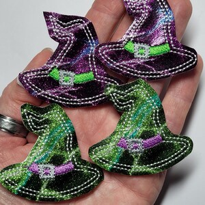 May include: Four witch hat appliques with a tie-dye pattern. The hats are purple and green with silver glitter and a green embroidered belt.