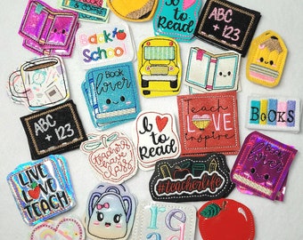 May include: A collection of colorful embroidered iron-on patches with various school-themed designs, including "Back to School", "Book Lover", "Live Love Teach", "I Love to Read", "ABC + 123", "Teacher Life", "Read", "Books", and "Teach Love Inspire".