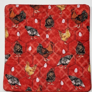 May include: Red fabric kitchen hot pad with a repeating pattern of chickens and eggs. The chickens are black, white, and brown with different patterns. The eggs are white.