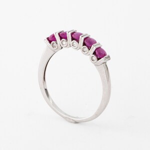 May include: A silver band ring with five pink oval gemstones and small diamonds set in the band.