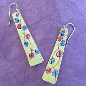 May include: A pair of dangle earrings with a yellow background and a design of red and blue circles connected by thin lines.