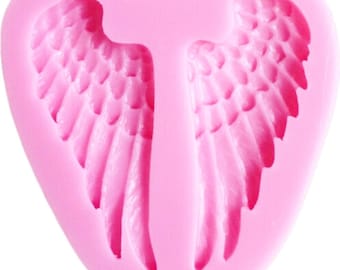 May include: Pink silicone mold shaped like a heart with two angel wings. The wings have detailed feathers.