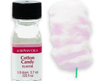 May include: A small clear glass bottle with a black lid. The bottle contains a clear liquid and has a pink label that reads "Lorann Oils Cotton Candy Flavor 1 fl dram 3.7 ml .125 fl oz".
