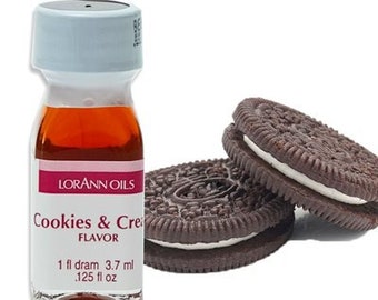 May include: A small glass bottle with a brown liquid inside. The bottle is labeled "Lorann Oils Cookies & Cream Flavor 1 fl dram 3.7 ml .125 fl oz". Two chocolate sandwich cookies are shown in the background.