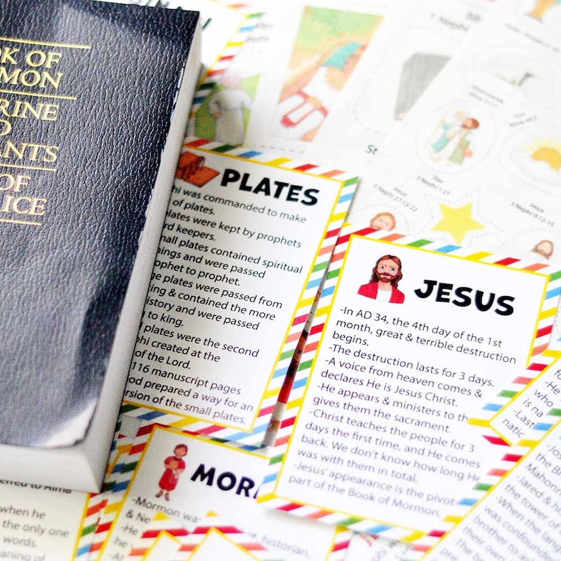 Peut inclure: Un livre de Mormon bleu fonc&eacute; &agrave; c&ocirc;t&eacute; de cartes &eacute;ducatives aux bordures ray&eacute;es color&eacute;es. Les cartes pr&eacute;sentent des illustrations et du texte sur des figures religieuses et des plaques historiques, avec des titres comme PLATES, JESUS et MORMON.