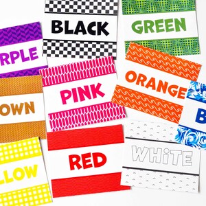 May include: A collection of rectangular cards featuring various colors and patterns. Each card displays the corresponding color name in bold text, including black, green, purple, pink, orange, brown, blue, yellow, red, and white.