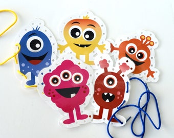 May include: A set of five die-cut monster-shaped cards with pre-punched holes along the edges for lacing. The monsters are colored blue, yellow, orange, pink, and dark red, each featuring large eyes, wide smiles, and various limb shapes.
