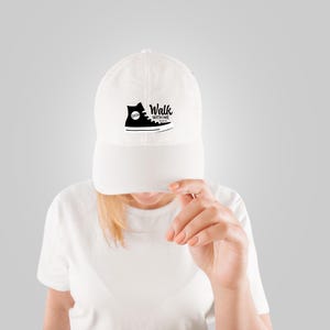 May include: White baseball cap with a black graphic of a high-top sneaker and the words "Walk With Me". The sneaker design includes the year "2024". The cap has a curved brim and a fabric strap closure.
