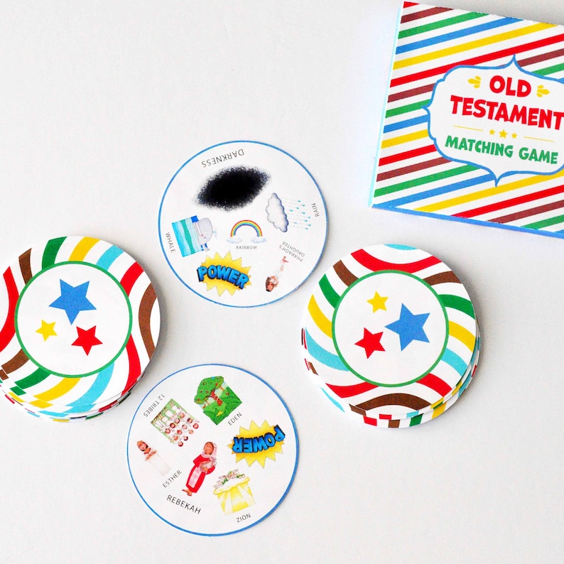 May include: A colorful Old Testament matching game with illustrated cards featuring images of characters, places, and events from the Bible. The cards are stacked in a pile and a box with the game title is visible in the background.