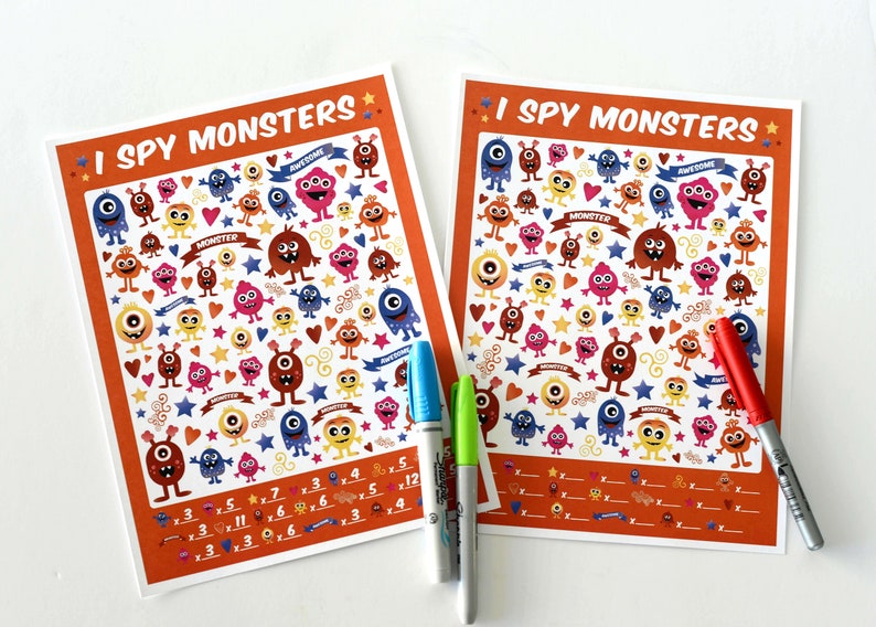 May include: Two orange and white printable "I Spy Monsters" activity sheets with colorful cartoon monsters, hearts, stars, and swirls. The sheets have a list of numbers and multiplication problems to solve.