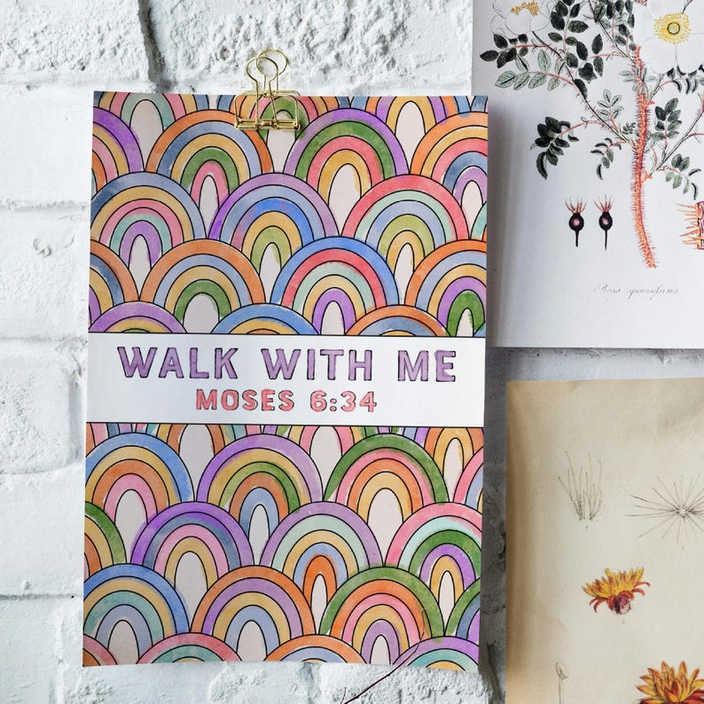 K&ouml;nnte beinhalten: Ein farbenfroher Kunstdruck mit einem sich wiederholenden Regenbogenmuster in Lila, Blau, Gr&uuml;n, Orange und Gelb. Der Text "WALK WITH ME MOSES 6:34" ist mittig platziert. Der Druck wird von einer goldenen Klammer gehalten.