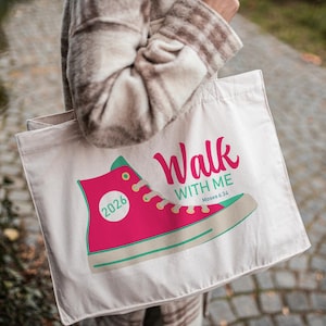 May include: Cream-colored tote bag featuring a pink high-top sneaker graphic with the text "Walk With Me" and "Moses 6:34". The sneaker has mint green and yellow accents, and the number "2026" is printed on the side.