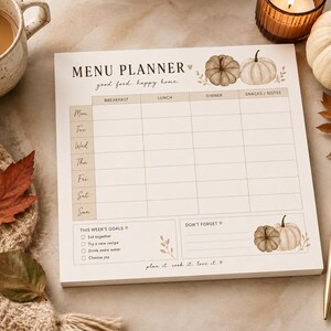 May include: A square paper menu planner pad featuring the text MENU PLANNER, good food. happy home., THIS WEEK'S GOALS, and DON'T FORGET. The grid includes days of the week, meal categories, and watercolor pumpkin illustrations in beige and brown tones.