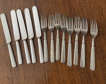 May include: A set of 10 silver-plated utensils, including 7 forks and 3 butter knives. The utensils are arranged in a row on a wooden surface.