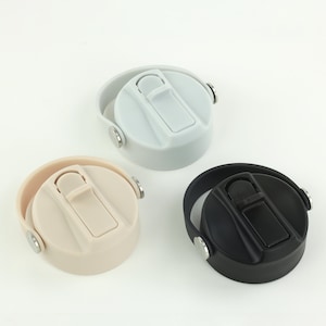 May include: Three water bottle lids in light grey, beige, and black. Each lid features a flip-top closure and a handle. The lids are made of plastic and have a simple, modern design. The lids are designed to fit a standard water bottle.