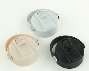 May include: Three water bottle lids in different colors: light gray, beige, and black. Each lid has a flip-top closure and a handle. The lids are made of plastic and have a simple, modern design. The lids are designed to fit a standard water bottle.