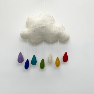 May include: A white felt cloud with a rainbow of felt raindrops hanging from it. The raindrops are purple, blue, teal, green, white, yellow, and red.