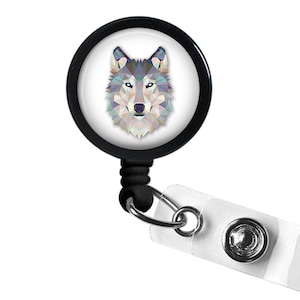 May include: A black retractable badge reel with a geometric wolf design. The wolf's head is composed of various pastel-colored triangles on a white background. The reel has a clear plastic strap and a metal clip.