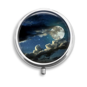 May include: A round silver compact mirror with a full moon and stars in a night sky design.