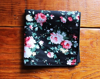May include: A black pocket square with a floral pattern featuring pink and white flowers on a black background.