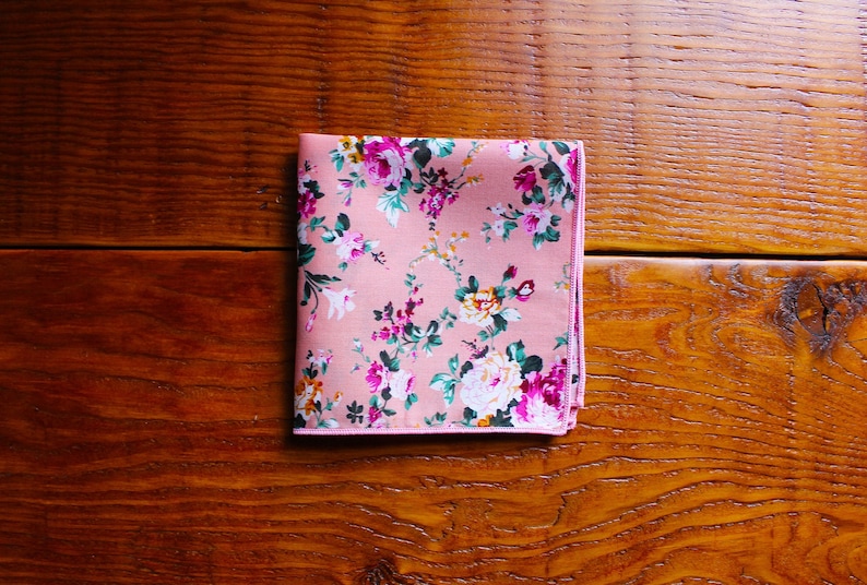 May include: A pink pocket square with a floral pattern. The flowers are in shades of pink, white, and green.