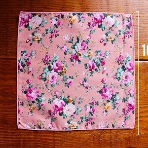 May include: A pink floral patterned fabric square with a pink border. The fabric measures 10 inches by 10 inches.