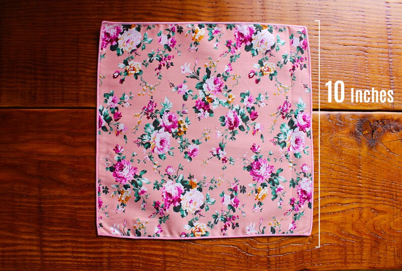 May include: A pink floral patterned fabric square with a pink border. The fabric measures 10 inches by 10 inches.