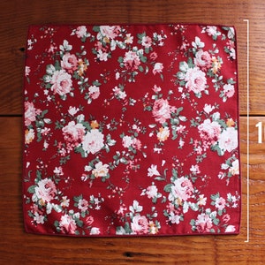 May include: A red pocket square with a white floral pattern. The pocket square measures 10 inches.
