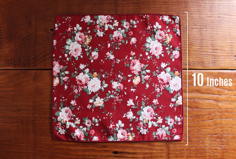 May include: A red pocket square with a white floral pattern. The pocket square measures 10 inches.