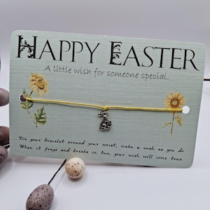 May include: A yellow string bracelet with a silver bunny charm. The bracelet is attached to a card with the text "HAPPY EASTER A little wish for someone special. Tie your bracelet around your wrist; make a wish as you do. When it frays and breaks in two, your wish will come true."