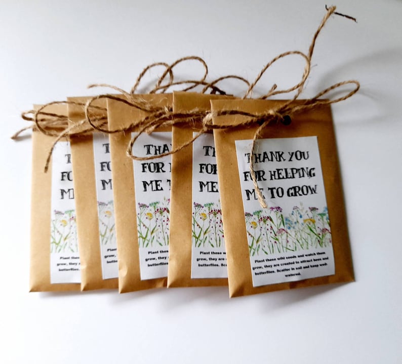 May include: Six brown paper seed packets tied with twine. Each packet has a printed label with a floral design and the text "Thank You for Helping Me to Grow".