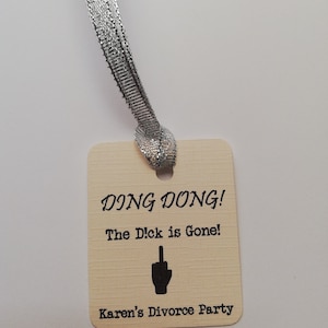 May include: A beige tag with a silver ribbon attached. The tag reads "DING DONG! The D!ck is Gone! Karen's Divorce Party".