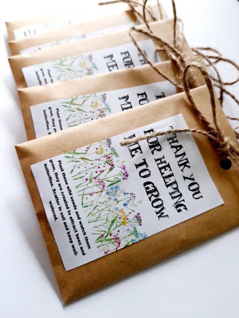 May include: Six brown paper envelopes with twine tied around them. Each envelope has a printed label with a floral design and the text "Thank you for helping me to grow". The envelopes contain wildflower seeds.