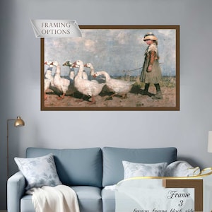 Puede incluir: Una impresión enmarcada representa a una persona joven guiando un grupo de gansos blancos a través de un campo. La obra de arte está en un marco marrón, con el texto "Framing Options" y "Frame 3 brown frame, black side" visible.