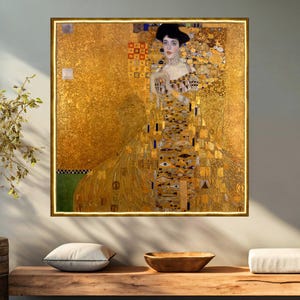 Puede incluir: Una pintura de una mujer con un vestido dorado con un patrón geométrico. El fondo también es dorado con un patrón geométrico. La mujer tiene el pelo oscuro y lleva un collar.