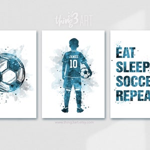 Pu&ograve; includere: Tre stampe ad acquerello con tema calcistico. La prima stampa presenta un pallone da calcio blu e bianco. La seconda stampa presenta una silhouette blu di un calciatore con il nome "JAMES" e il numero "10" sulla maglia. La terza stampa presenta il testo "EAT SLEEP SOCCER REPEAT" in blu.