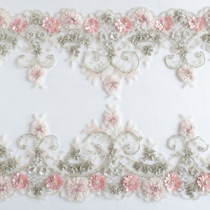 Puede incluir: Dos filas de encaje floral delicado con flores rosas y blancas y lentejuelas plateadas. El encaje es perfecto para agregar un toque de elegancia a cualquier proyecto.