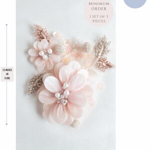 May include: A set of three delicate pink flower embellishments with pearl and rhinestone accents. Each flower measures 3.5 inches or 9 cm in diameter. The embellishments are perfect for adding a touch of elegance to clothing, accessories, or home decor.