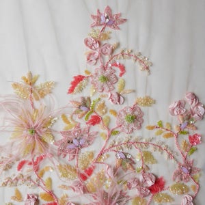 May include: Pink, yellow, and green beaded floral embroidery on a white sheer fabric. The embroidery features delicate flowers, leaves, and feathers.